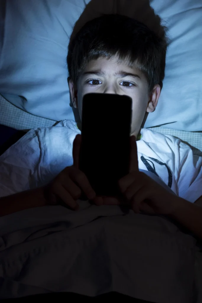 pessoa com vício em celular olhando para o celular no escuro, com o rosto iluminado pela tela